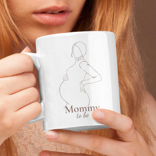 Close-up van een witte Mommy to be mok vastgehouden door een vrouw waarbij het minimalistische lijnontwerp duidelijk zichtbaar is