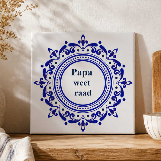 Delfts blauw keramisch tegeltje met de tekst “Papa weet raad” op houten plank in warme landelijke keukenstijl