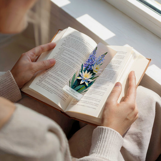 vrouw die een boek leest, op de open pagina van het boek ligt een bookmark. Geboorte bloem boekenlegger voor de maand juli, met kunstzinnige illustratie van Ridderspoor & Waterlelie.