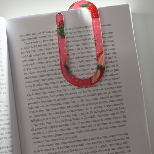 Grote paperclip met aardbeienpatroon bevestigd aan een open boek