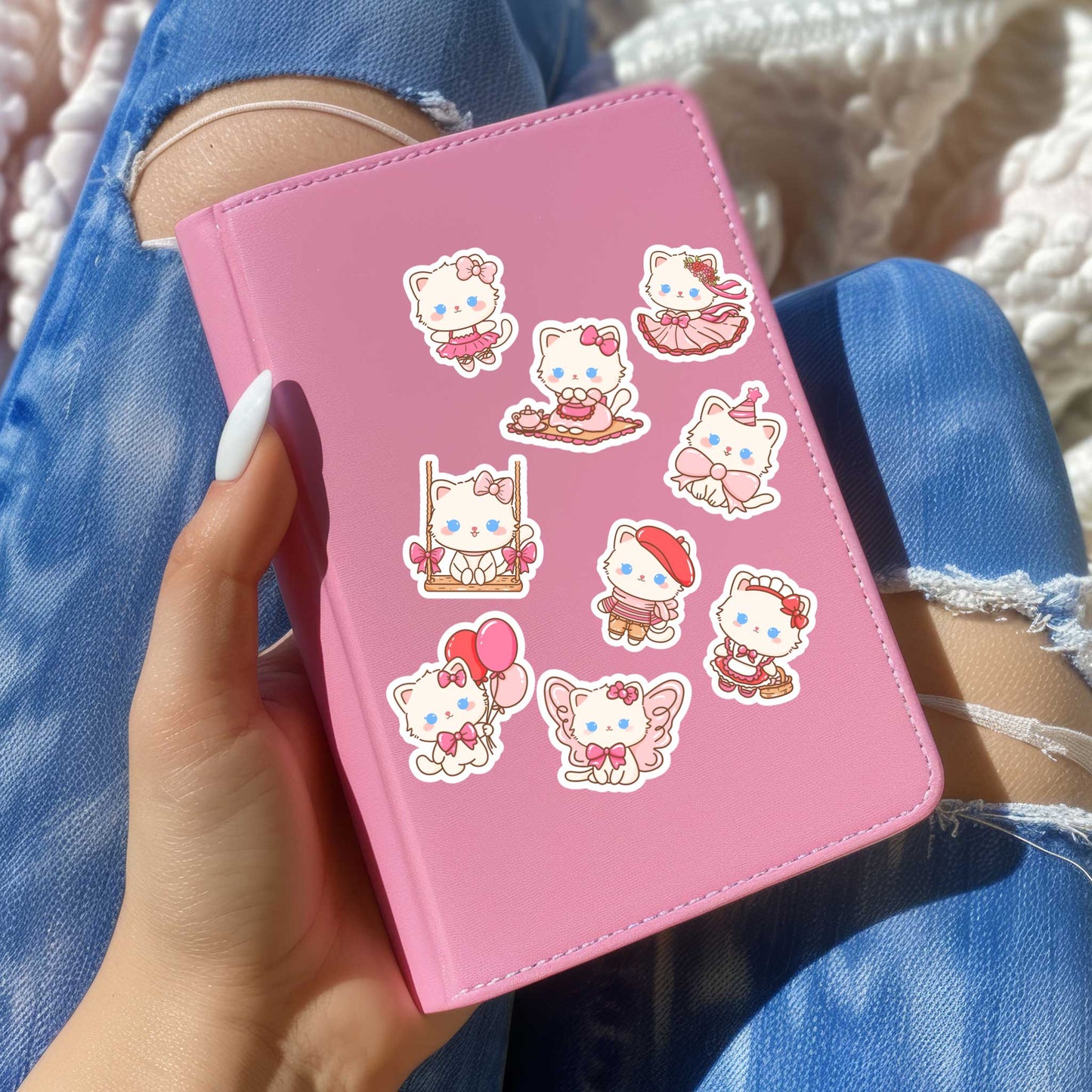 Roze planner versierd met kawaii kattenstickers in pastelstijl, vastgehouden op schoot bij zonlicht