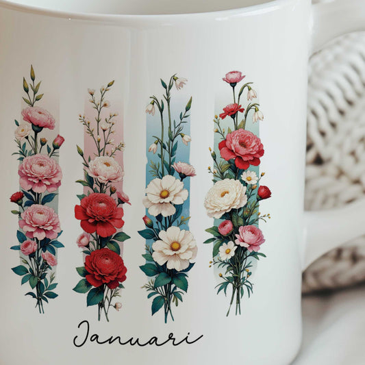 Close-up van de witte mok met de geboortebloem van januari in brush effect, waarop de bloemenillustratie en de tekst 'Januari' duidelijk zichtbaar zijn.