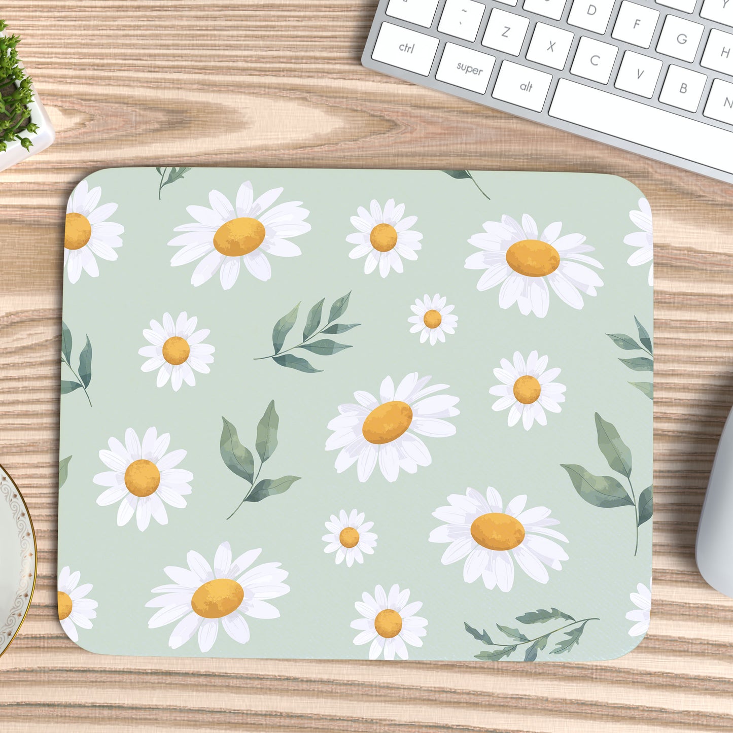 muismat met een bloemenpatroon, Margrietjes en blaadjes op een licht groene ondergrond op een grenen bureau blad met een wit toetsenbord