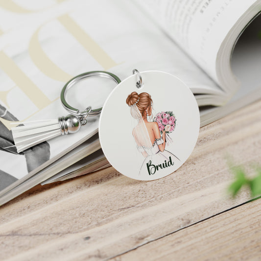 Ronde sleutelhanger met bruid en roze rozen, liggend op een tijdschrift