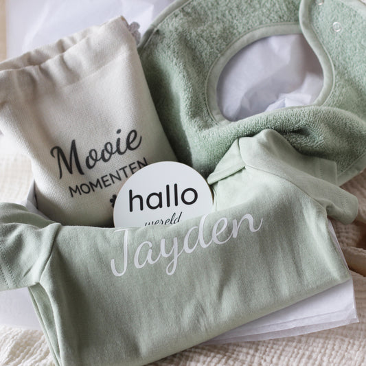 bovenaanzicht van baby giftbox met groen rompertje, slabbetje, linnen zakje en mijlpaalschijfjes