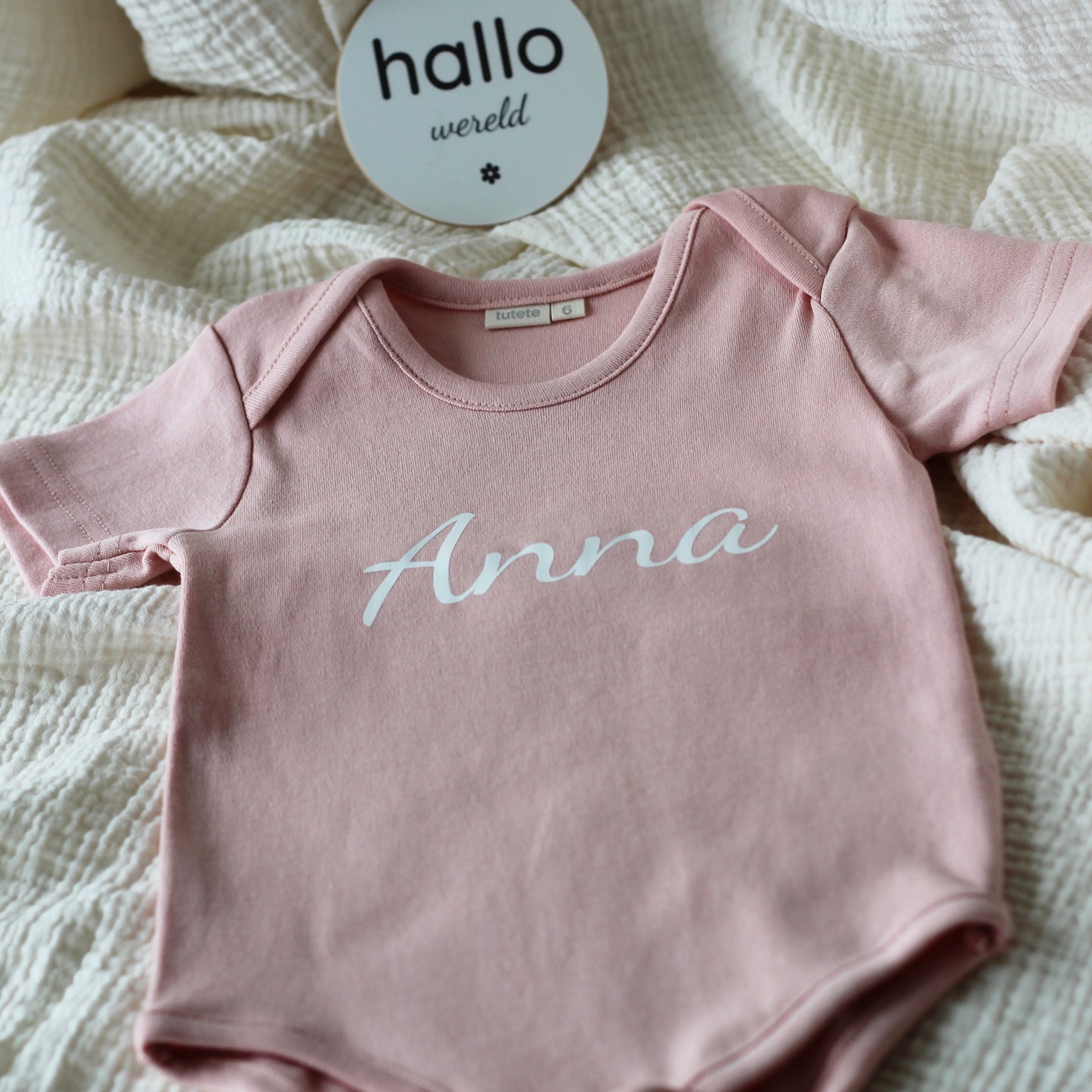 Roze babyrompertje met de naam Anna gedrukt op de voorkant