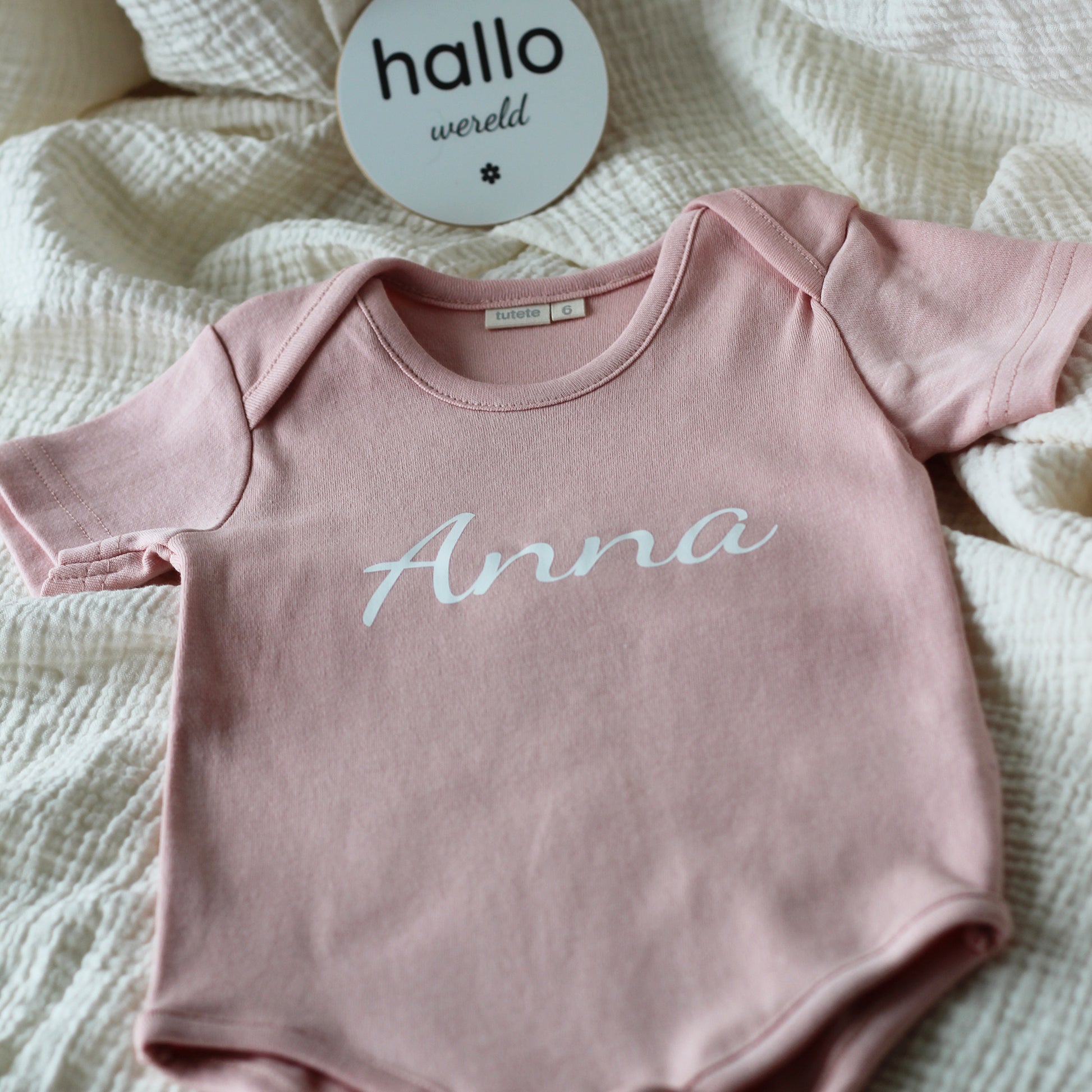 Roze babyrompertje met de naam Anna gedrukt op de voorkant