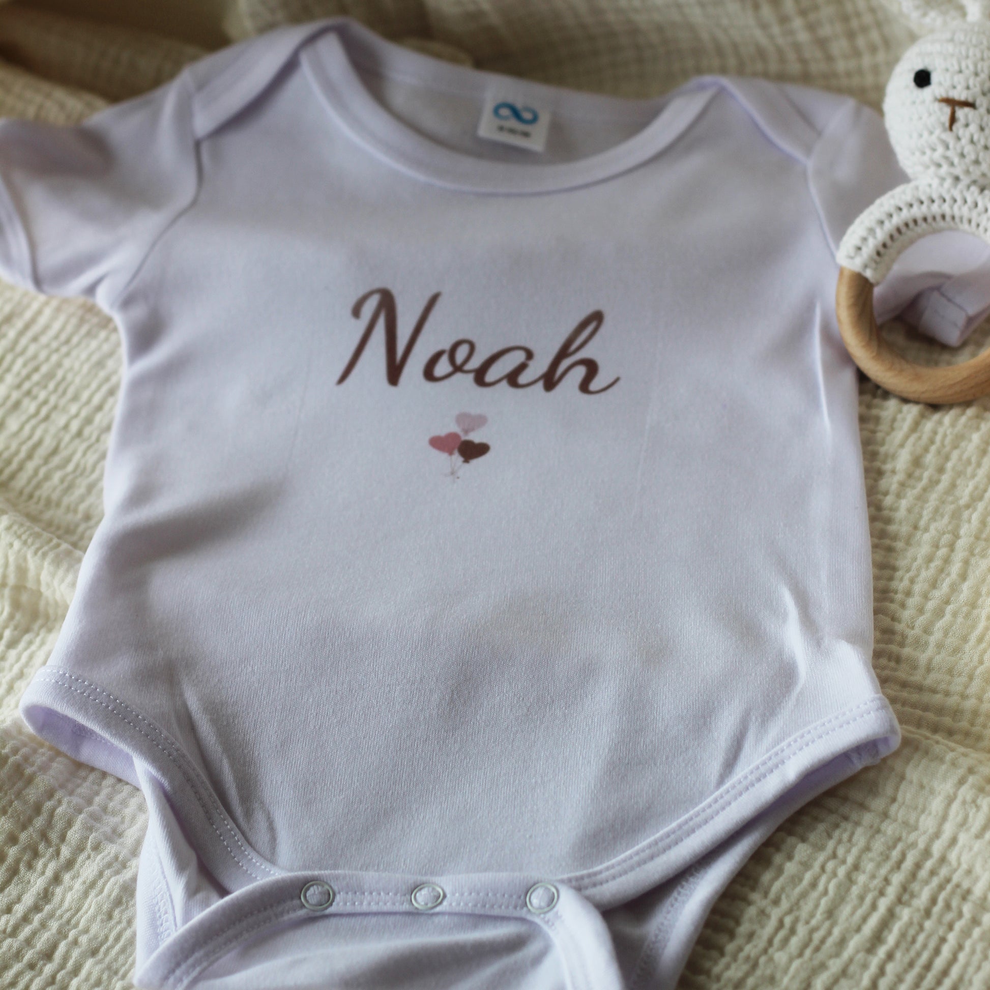 Wit baby rompertje met naam Noah en kleine ballonillustratie