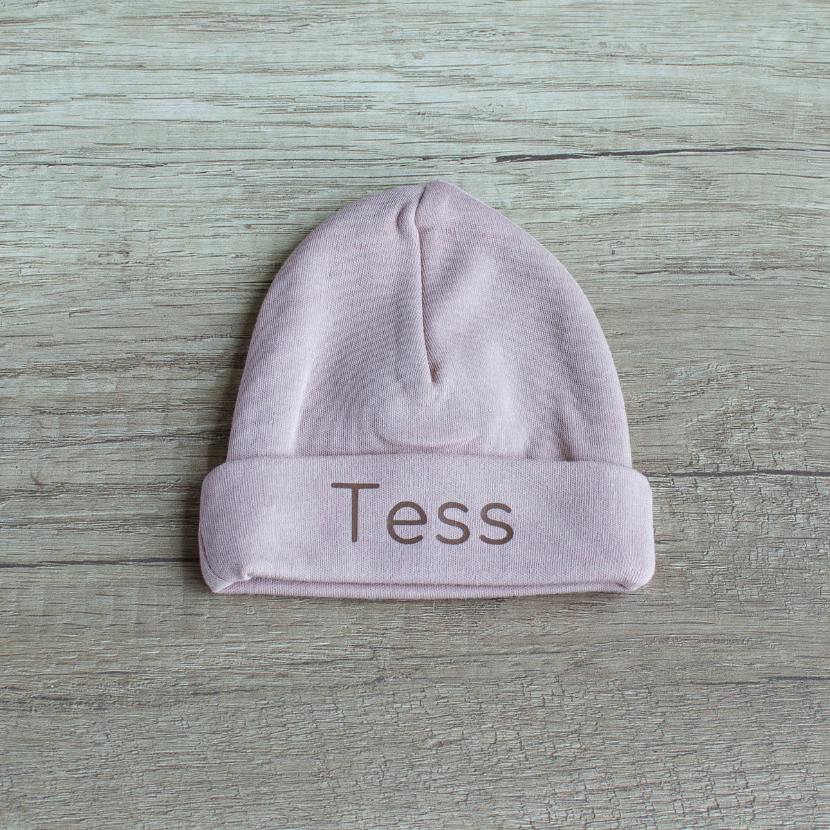 Pinkstone newborn babymutsje met omslag, gepersonaliseerd met de naam Tess in chocoladebruin.