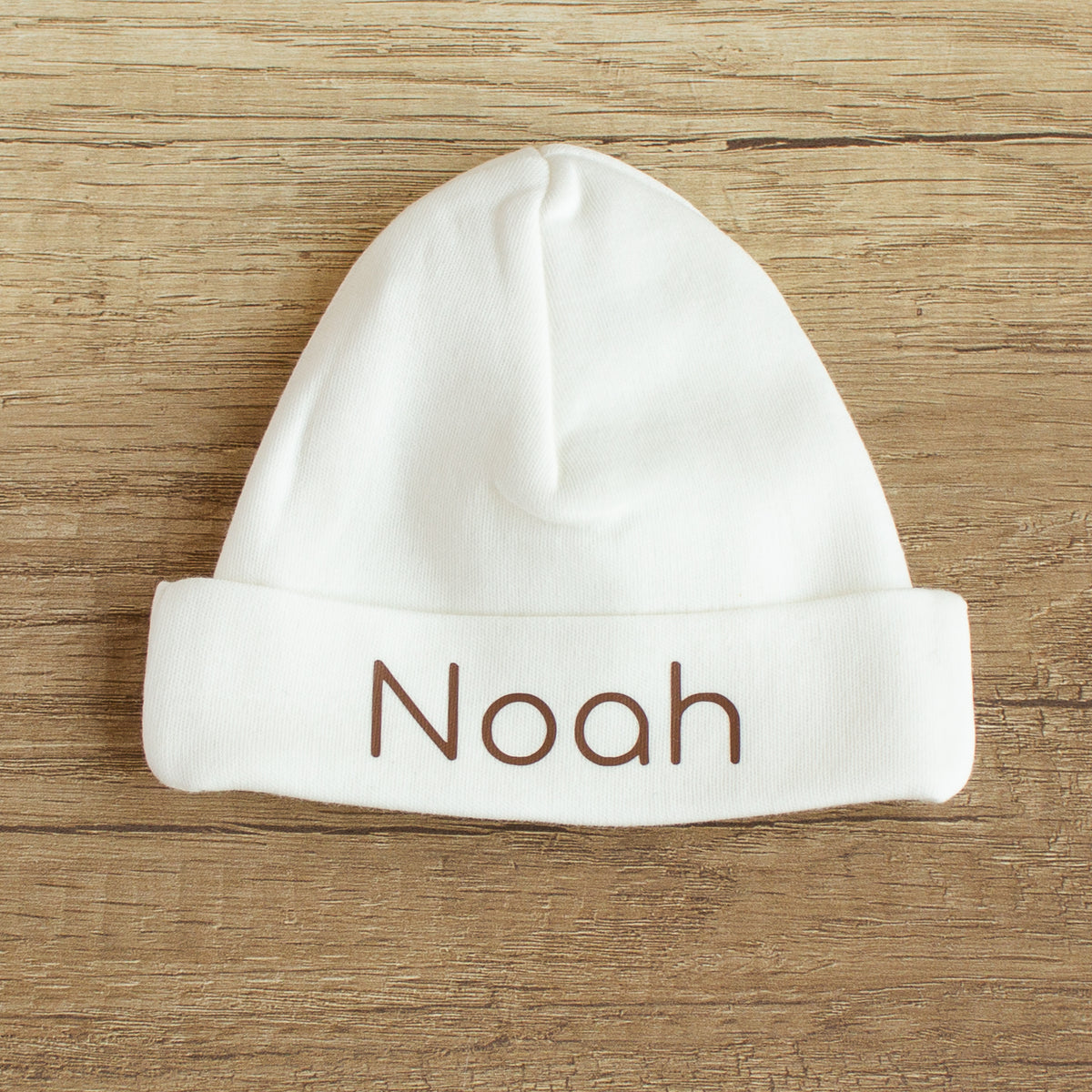 Ecru newborn mutsje maat 50/56 met omslag, gepersonaliseerd met de naam Noah in bruine letters.