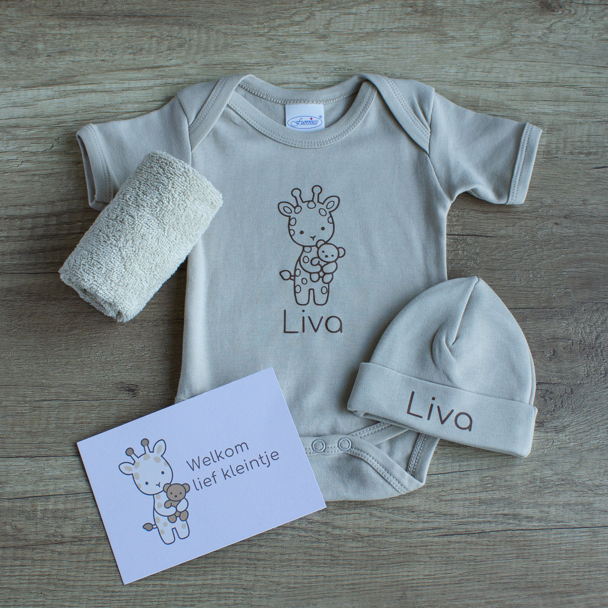 Newborn cadeauset Girafje in zandkleur met gepersonaliseerde romper en muts met naam Liva, spuugdoekje en kaartje ‘Welkom lief kleintje’.