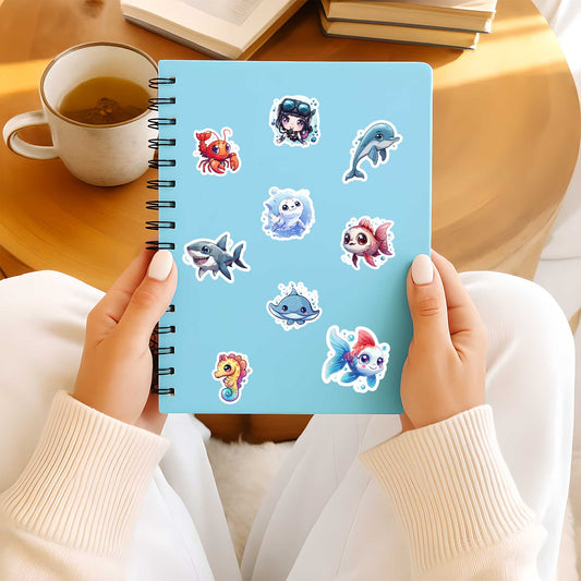 Blauw notitieboek versierd met kawaii zeewereld stickers zoals dolfijn, zeepaardje en haai