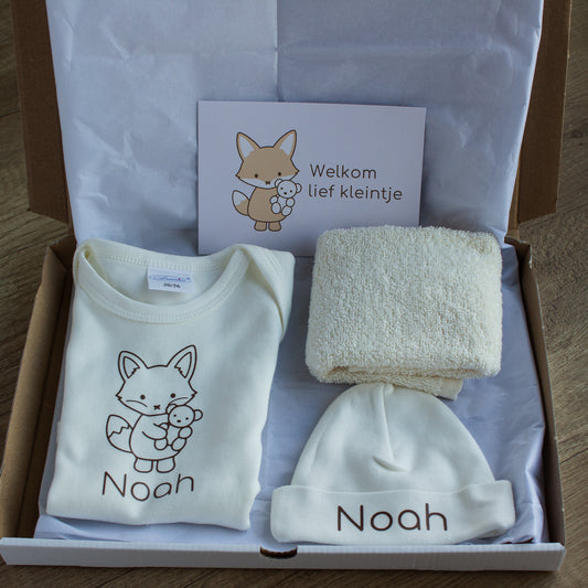 Foto 2 – open doos
Open verzenddoos met ecru newborn cadeauset, bestaande uit gepersonaliseerd rompertje en mutsje met naam Noah, spuugdoekje en cadeaukaartje met vosje.