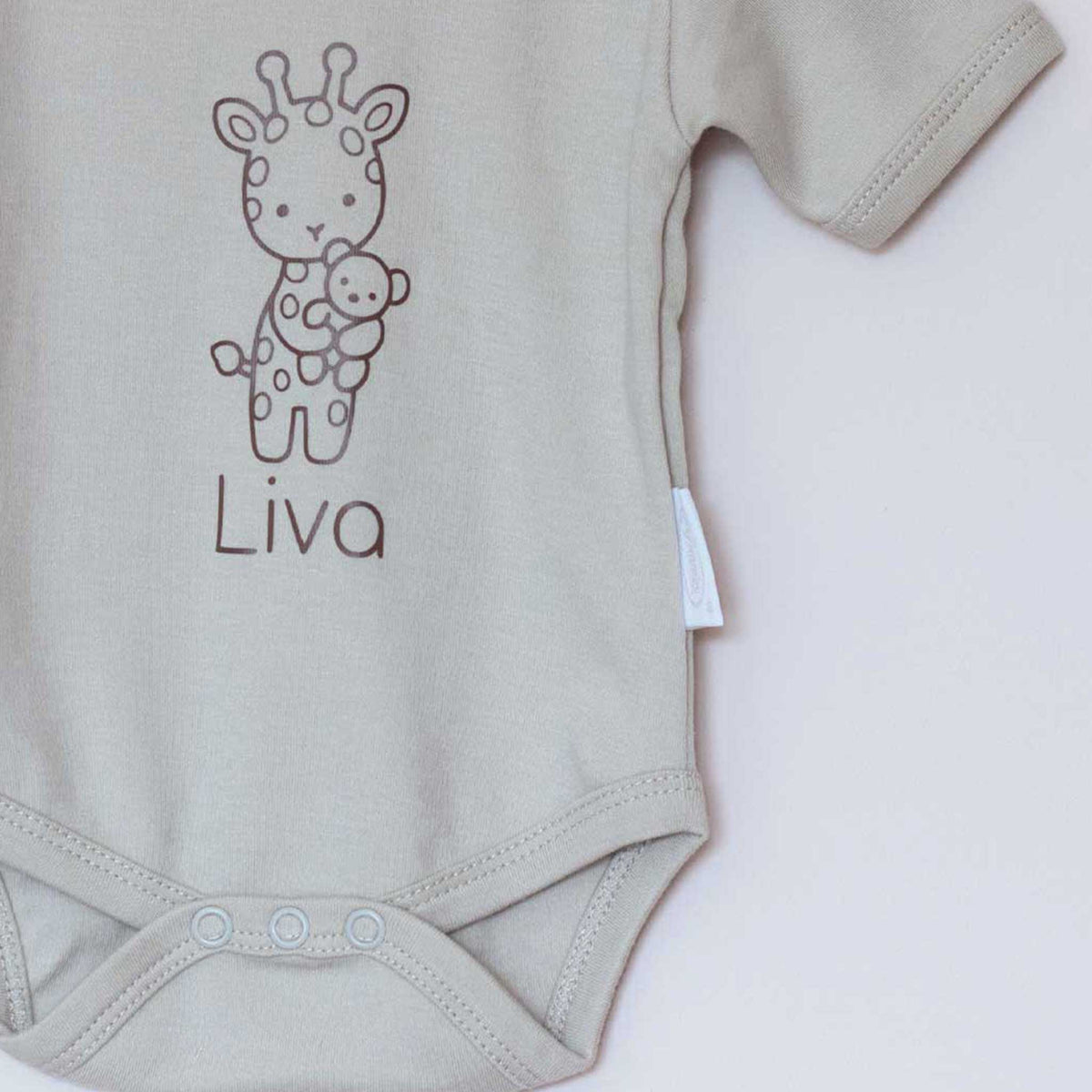 Close-up van Sandstone Grey babyromper met lijntekening van een giraf en de gepersonaliseerde naam eronder