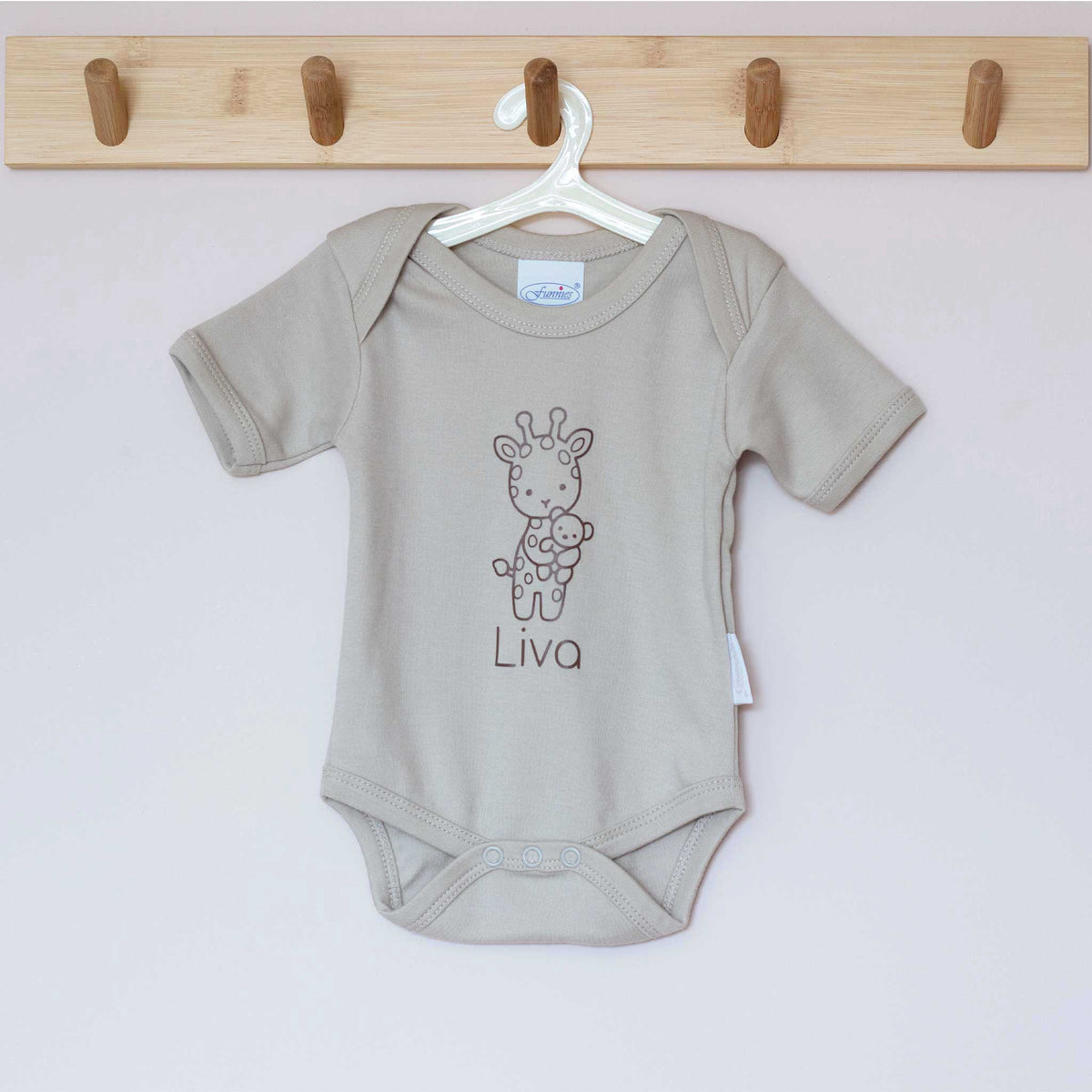 Sandstone Grey babyromper aan een houten hanger, bedrukt met een giraf en gepersonaliseerde naam