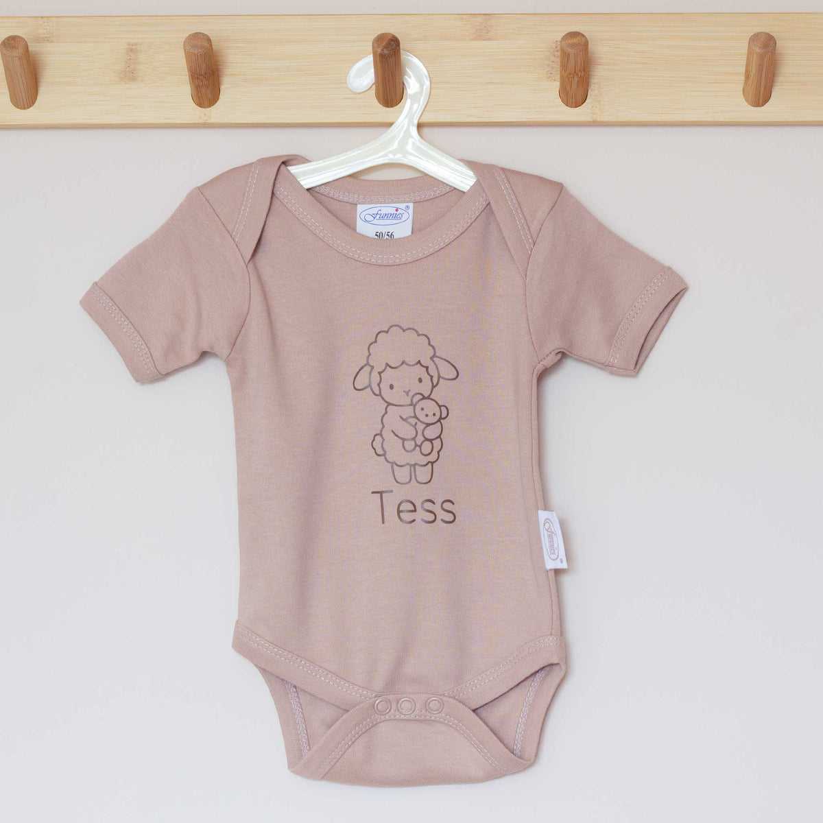 Pinkstone babyromper aan een houten hanger, bedrukt met een lammetje en gepersonaliseerde naam