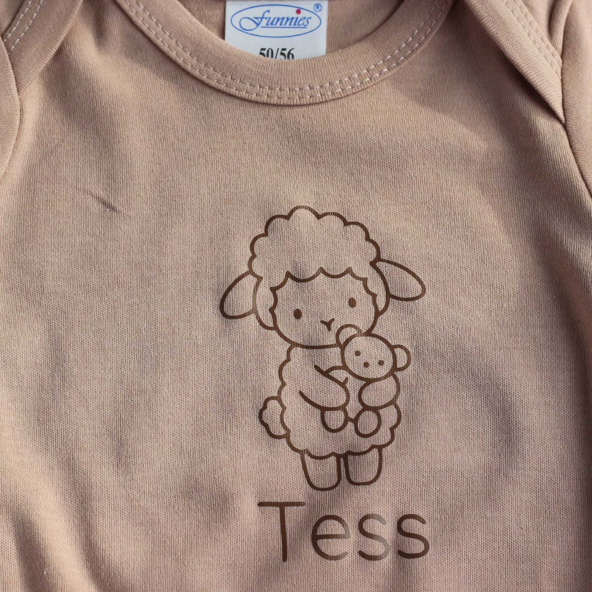 Close-up van Pinkstone babyromper met lijntekening van een lammetje en de gepersonaliseerde naam eronder
