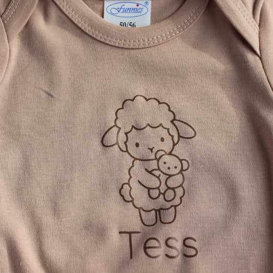 Close-up van Pinkstone babyromper met lijntekening van een lammetje en de gepersonaliseerde naam eronder