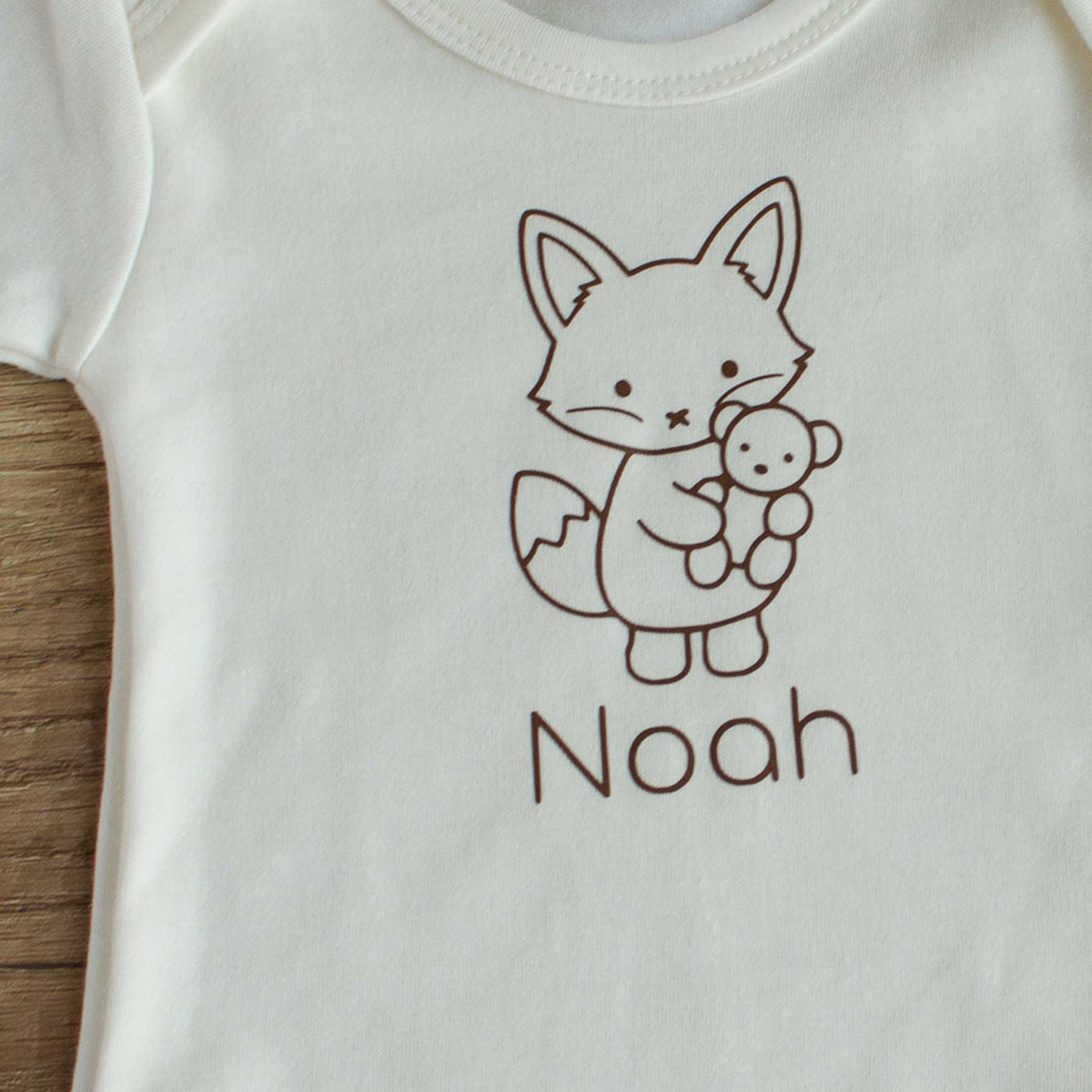 Close-up van Ecru babyromper met lijntekening van een vosje en de gepersonaliseerde naam eronder