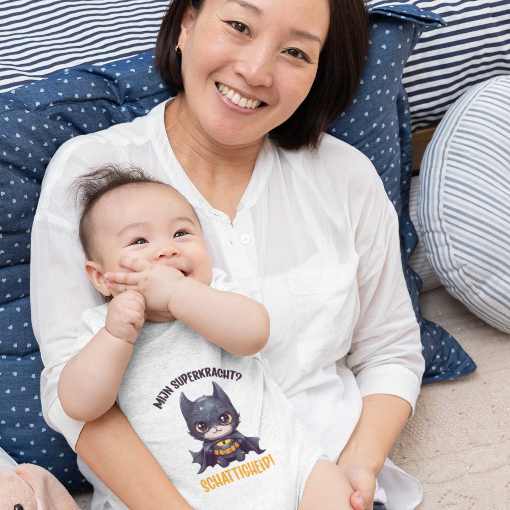 Baby op schoot in rompertje met grappige superheld-illustratie en tekst “Mijn superkracht? Schattigheid!” – origineel babycadeau