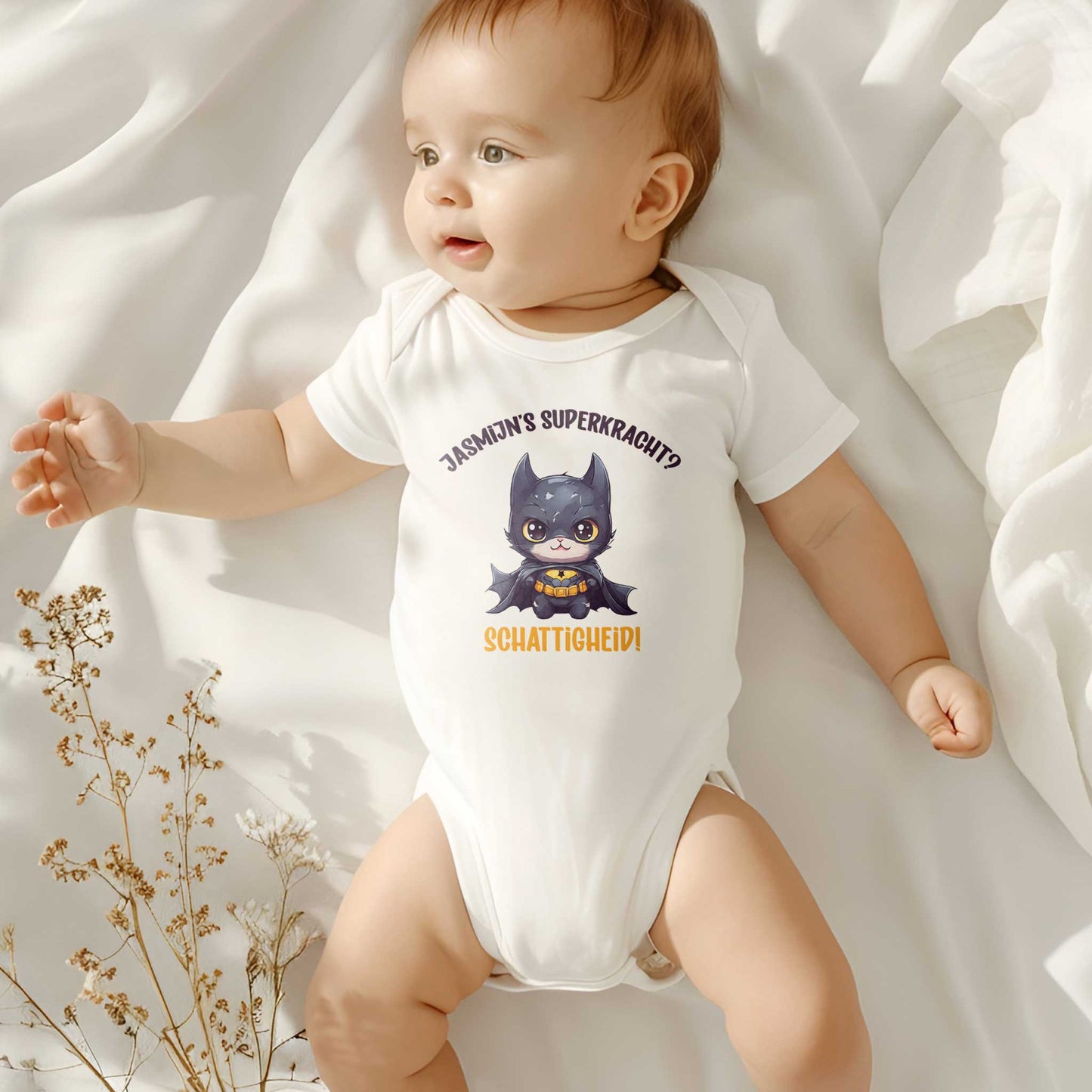 Lachende baby op bed in rompertje met superheld-kat en tekst “Jasmijn’s superkracht? Schattigheid!” – origineel rompertje met naam