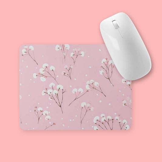 Muismat met roze achtergrond en witte bloemen, witte muis erop, gefotografeerd tegen roze achtergrond