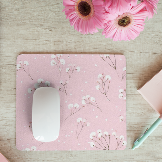 Muismat 22×19 cm met roze achtergrond en witte bloemen, witte muis erop, gefotografeerd op houten bureau met roze bloemen