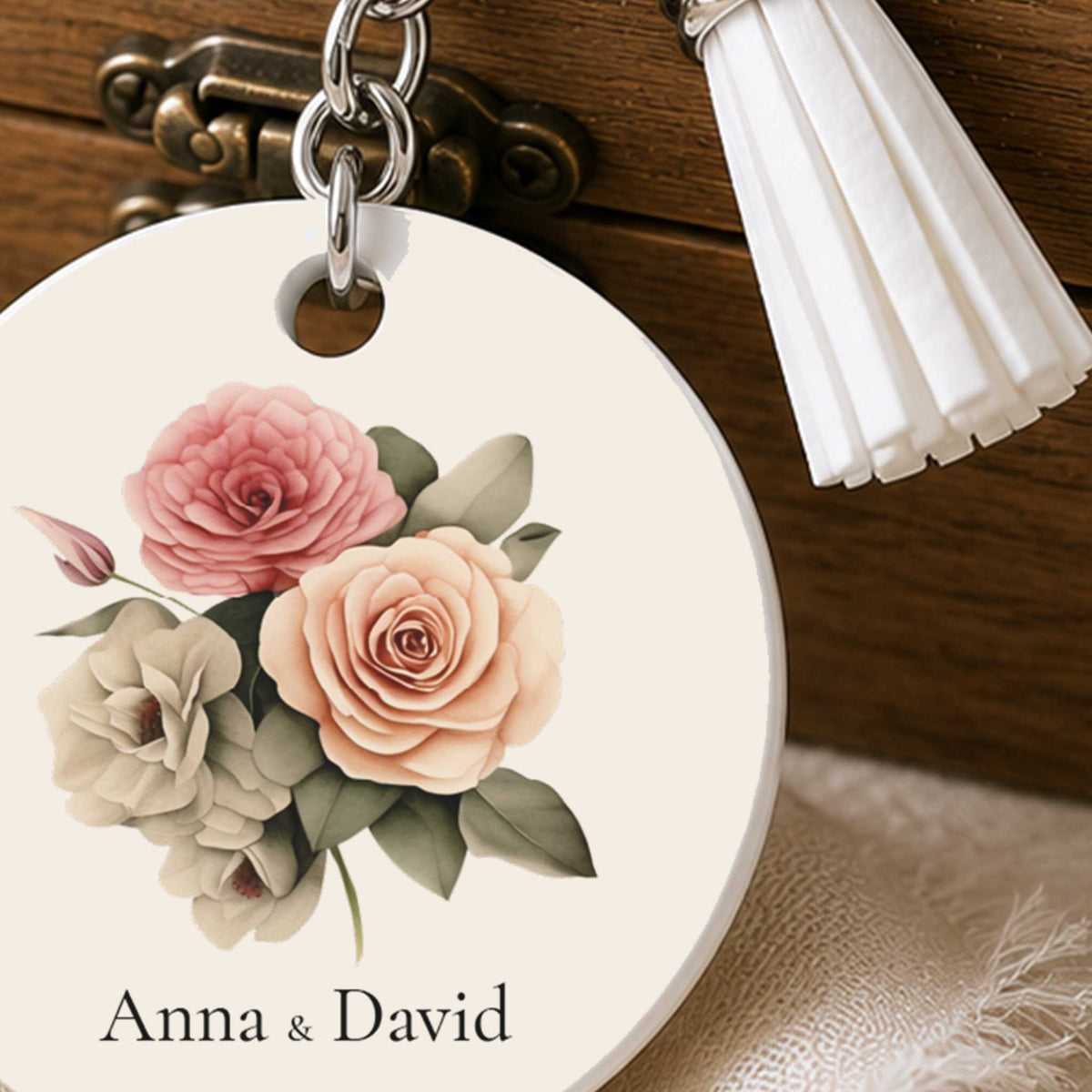 Close-up van gepersonaliseerde bruiloft sleutelhanger met rozenboeket, namen en witte kwast
