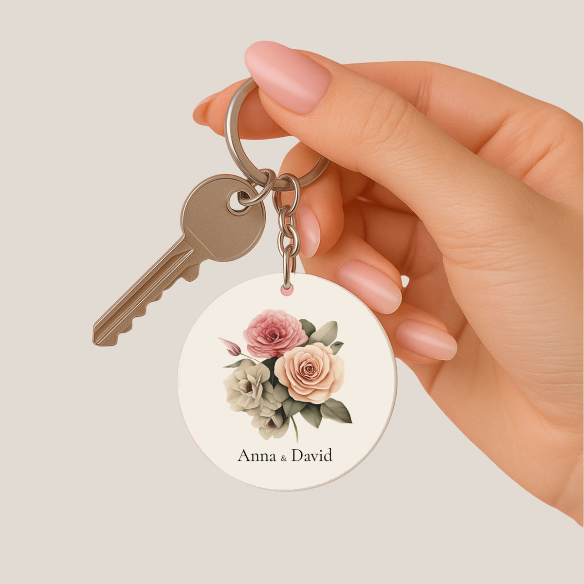 Ronde bruiloft sleutelhanger met roze en perzikkleurige rozen en gepersonaliseerde namen in een hand