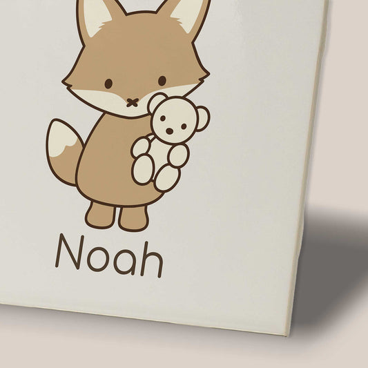 Close-up van een keramisch tegeltje met een vosje dat een beertje vasthoudt en de naam Noah.