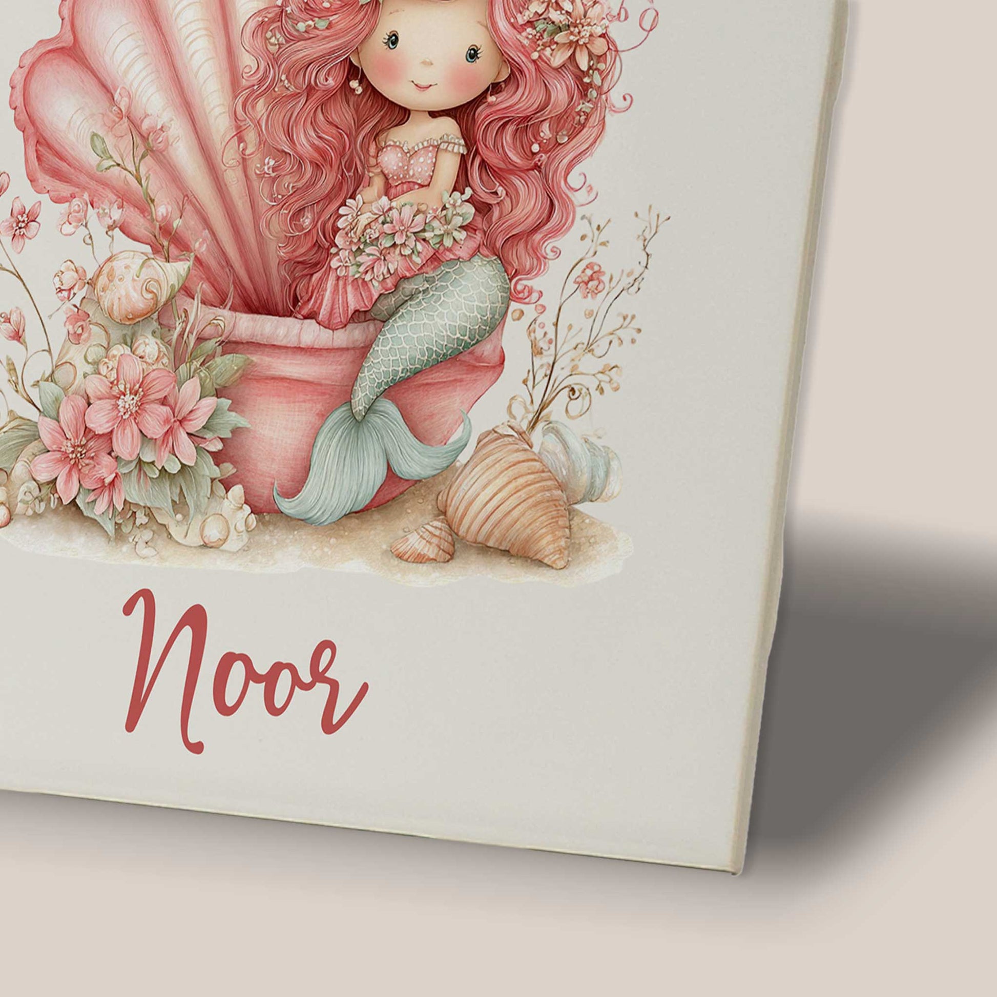 Close-up van een keramisch tegeltje met een gedetailleerde illustratie van een roze zeemeermin. De afbeelding laat de bloemen, de grote schelp, de mintgroene zeemeerminstaart en de naam Noor onder het ontwerp duidelijk zien.
