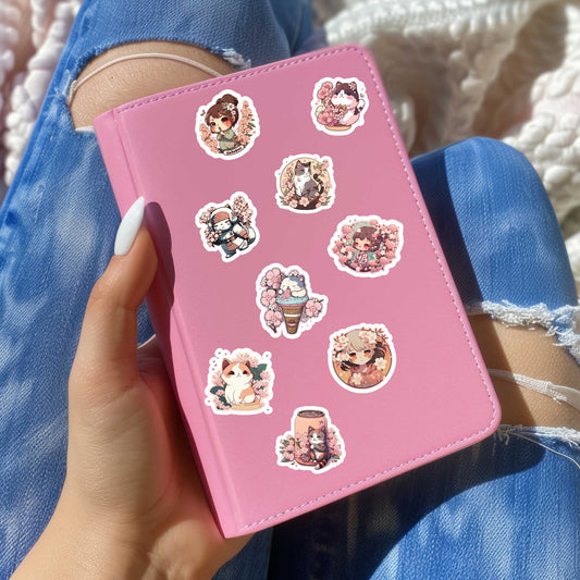 Roze notitieboekje versierd met anime kersenbloesemstickers, vastgehouden door een hand met witte nagellak