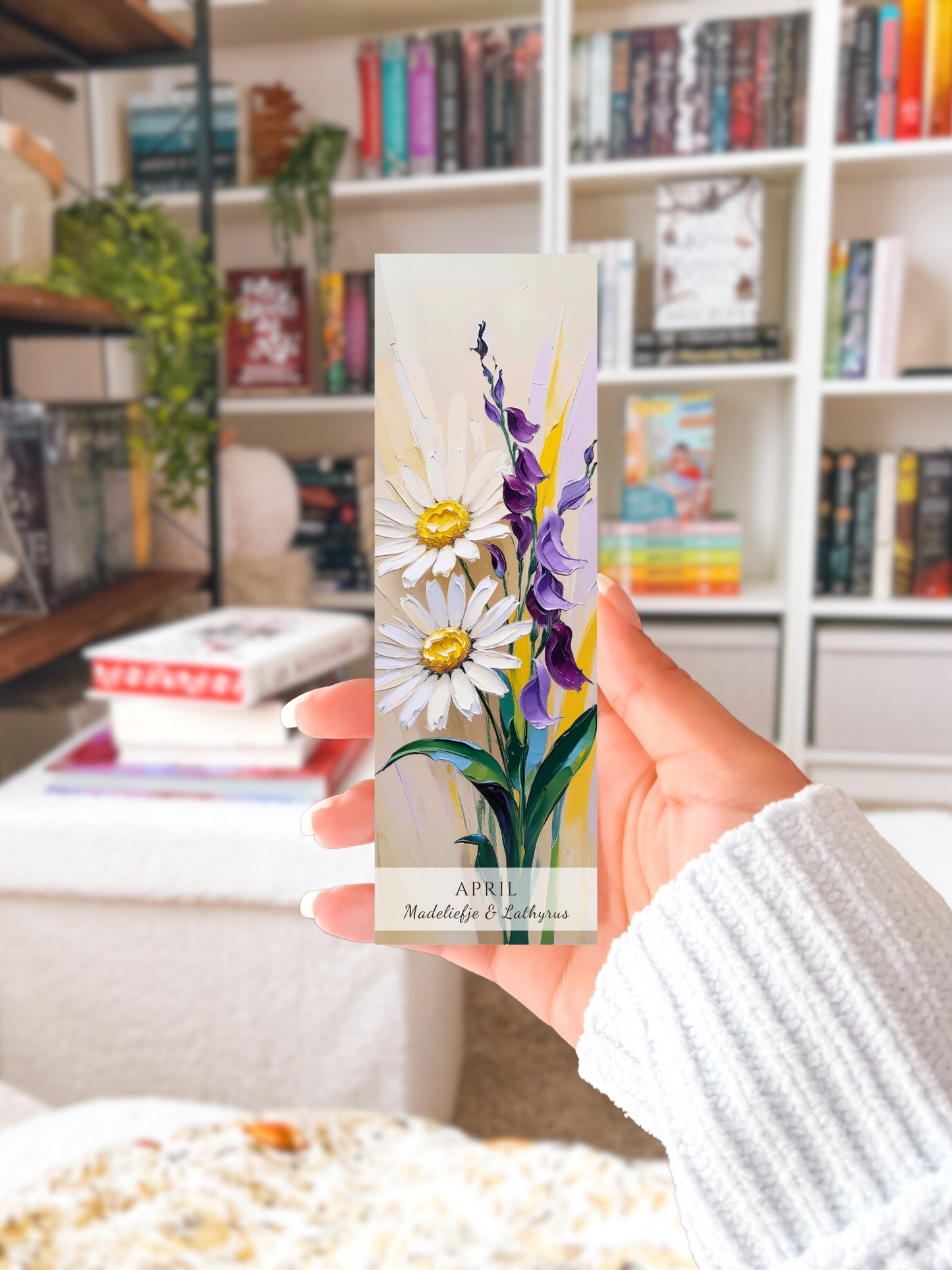 vrouwenhand met geboorte bloem boekenlegger voor de maand april, met  kunstzinnige illustratie van Madeliefje & Lathyrus