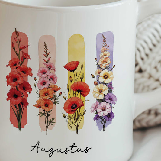 Close-up van een witte mok met de geboortebloemen gladiool en klaproos en de tekst Augustus.