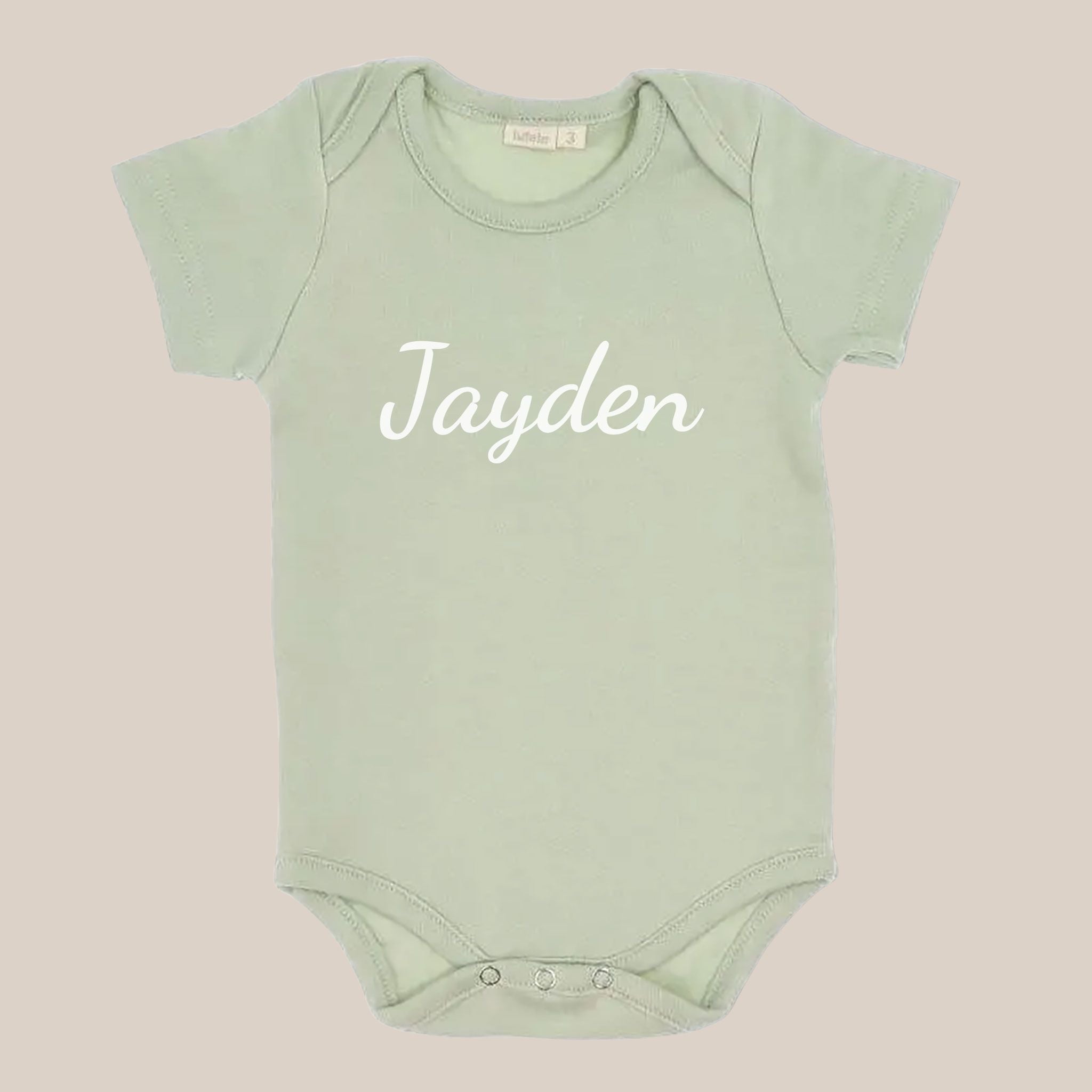 Groen babyrompertje met een naam in witte sierletters op de voorkant