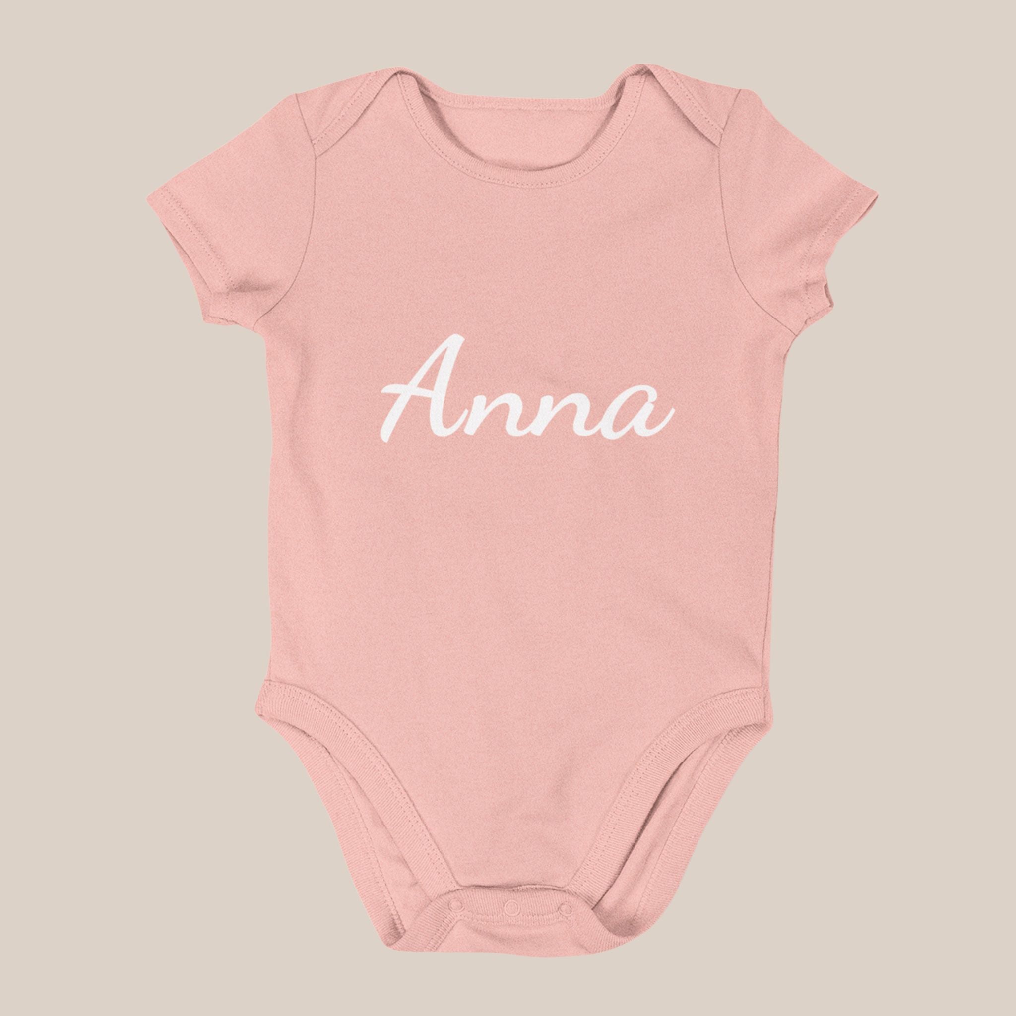 Roze babyrompertje met de naam Anna in witte sierletters op de voorkant