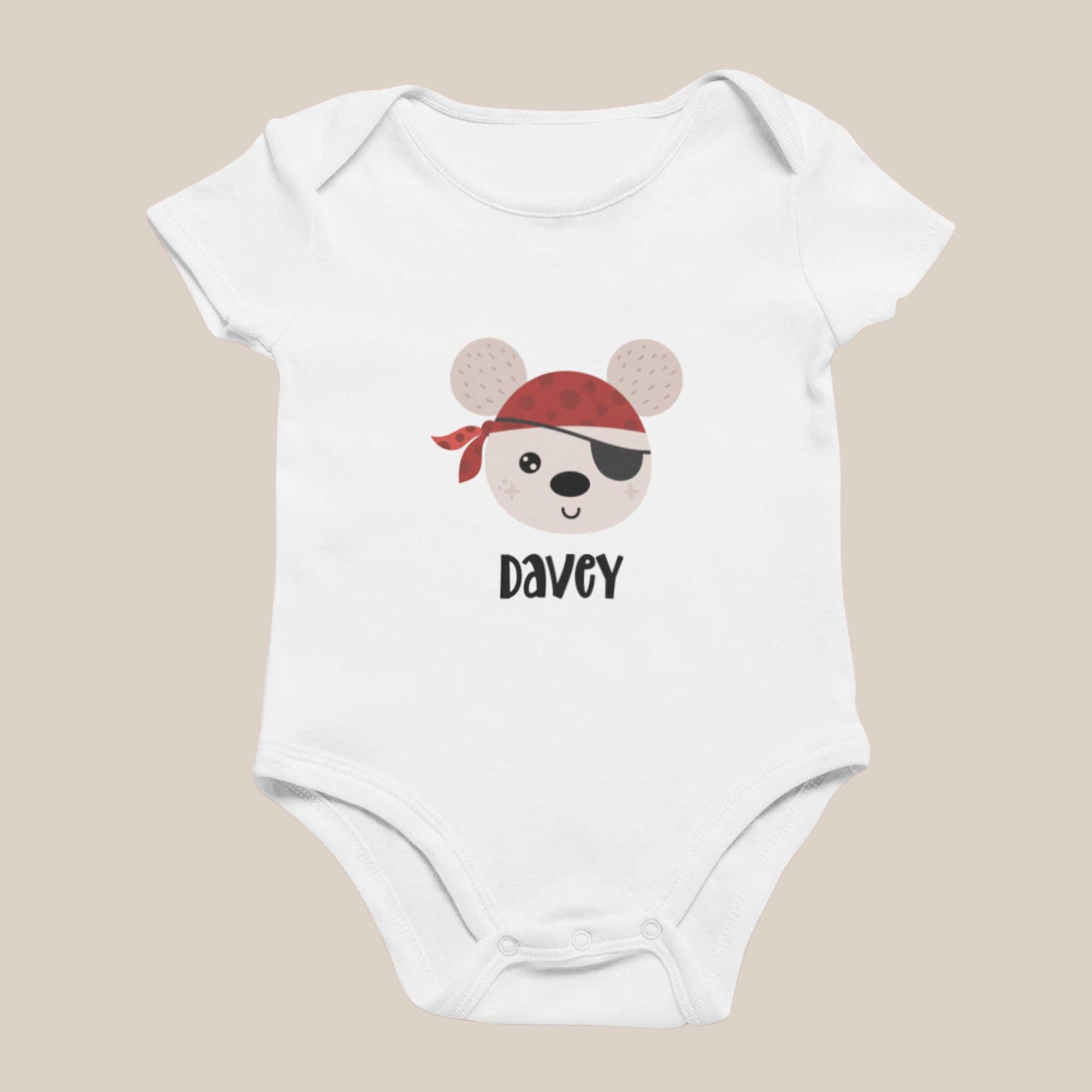 Wit babyrompertje met een illustratie van een beer met een rode bandana en ooglapje en een naam eronder