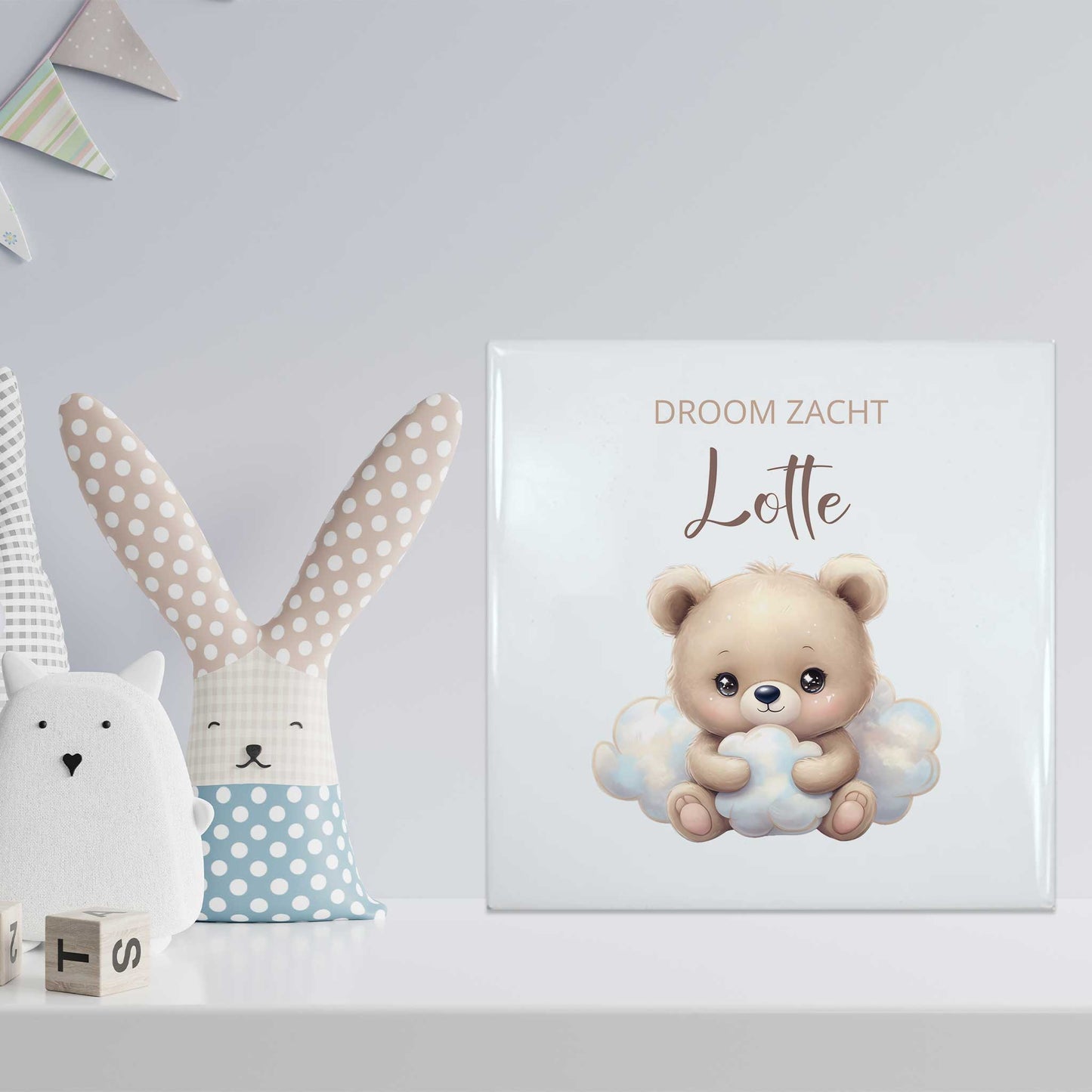 Babytegeltje met beer en naam Lotte op een witte plank tussen knuffels