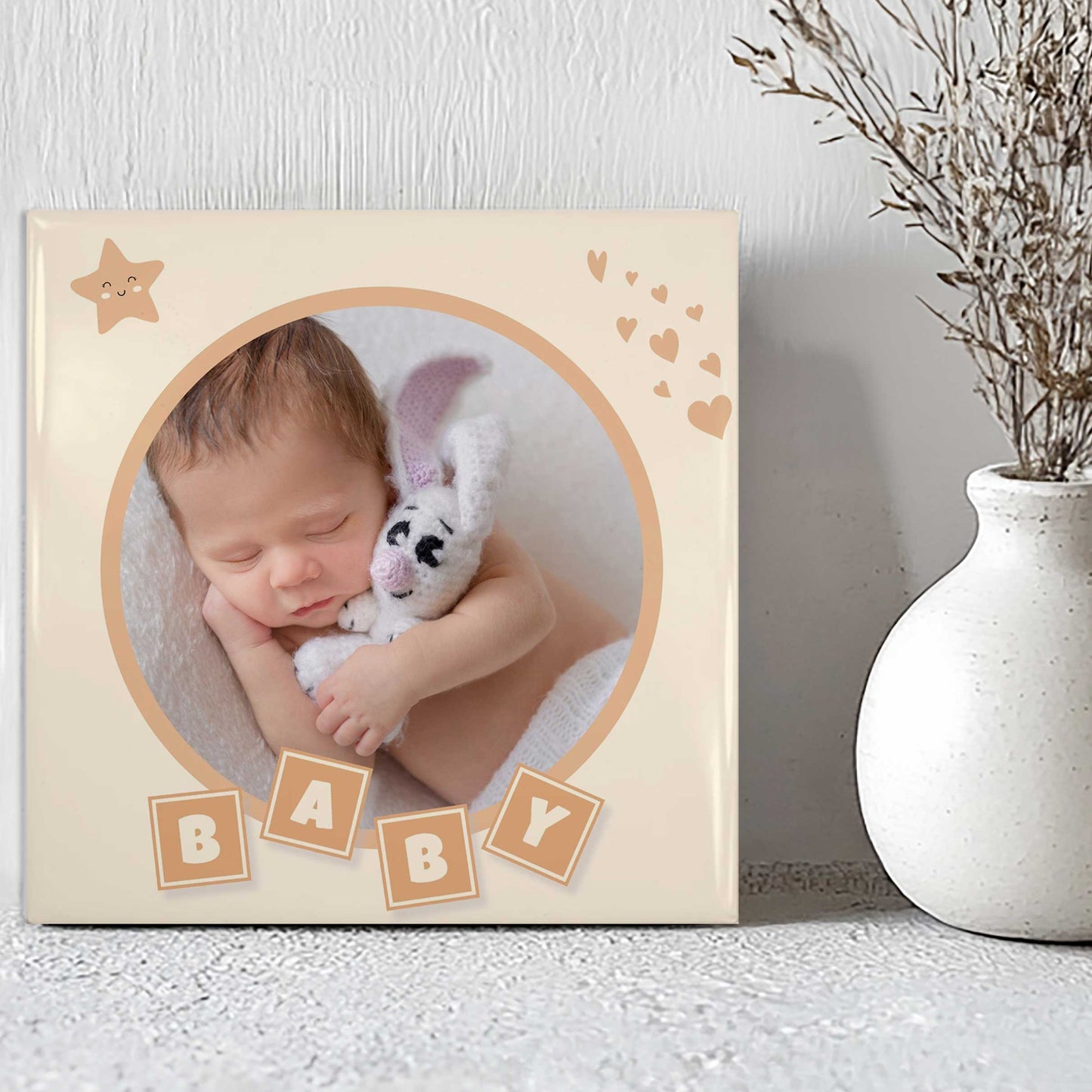Babytegeltje met zachte illustraties en foto van slapende baby naast witte vaas