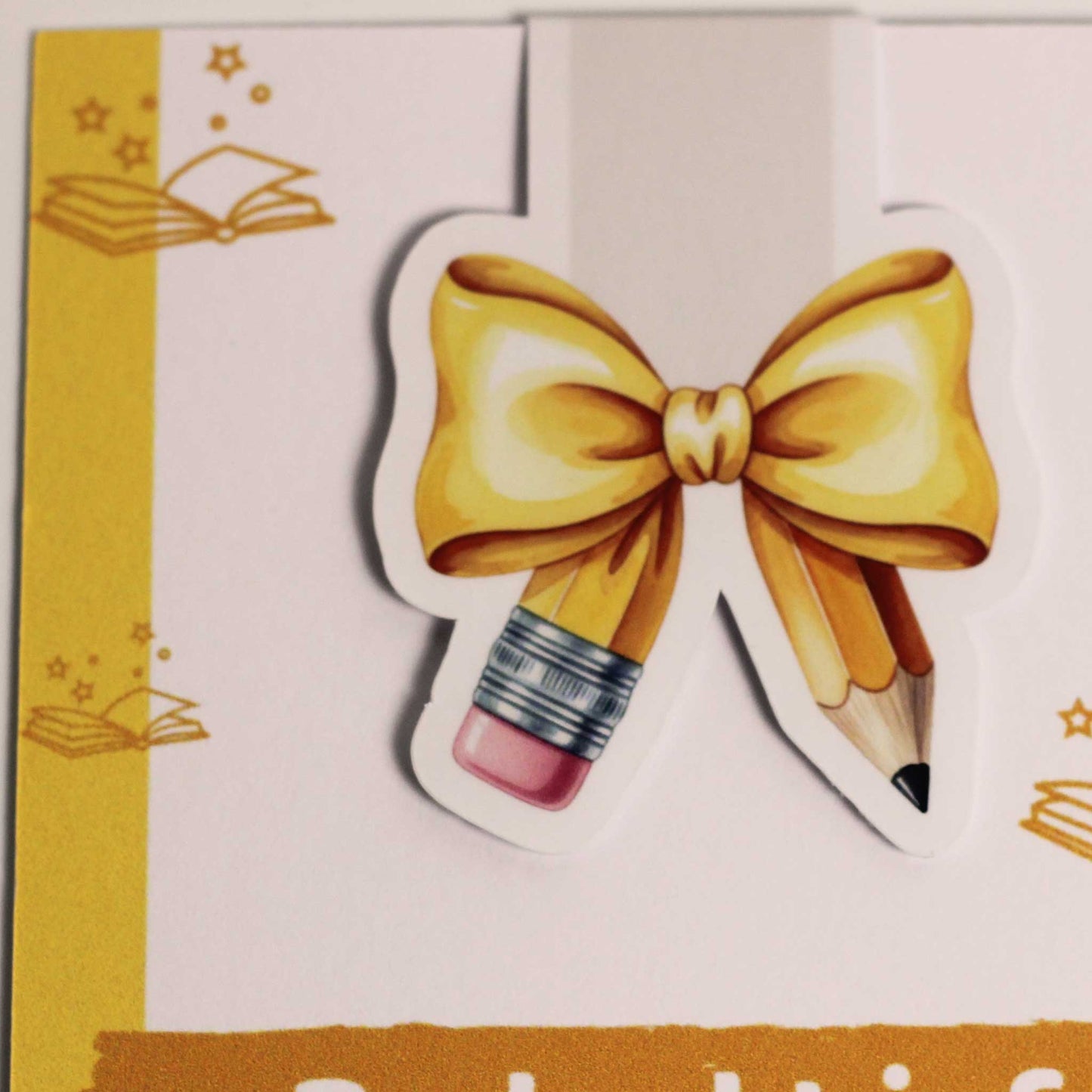 Detailfoto van een magnetische boekenlegger met geel potlood, strik en witte rand op een lichte achtergrond