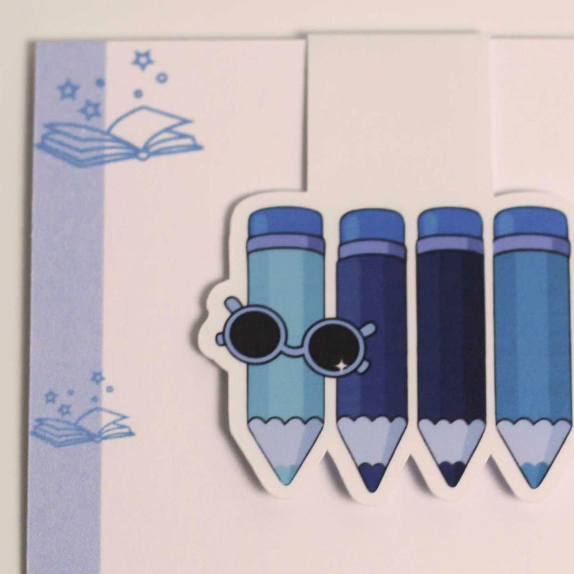 Detailfoto van een magnetische boekenlegger met blauwe potloden en zonnebril op lichte achtergrond