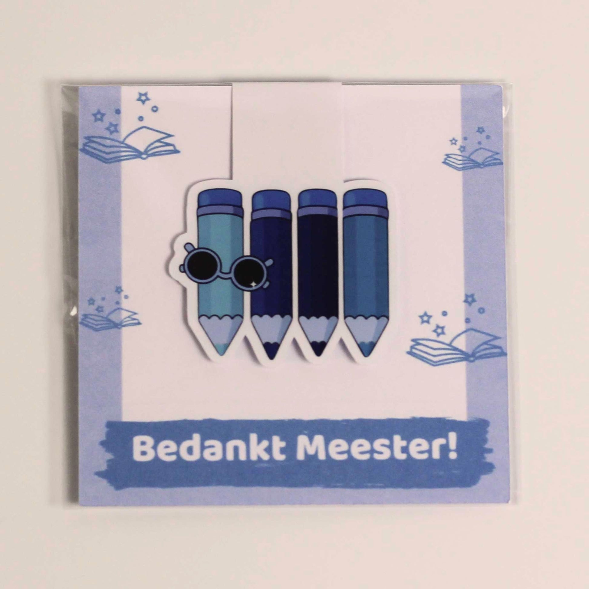 Magnetische boekenlegger voor meester met blauwe potloden en zonnebril op een kaartje met de tekst Bedankt Meester in transparante verpakking