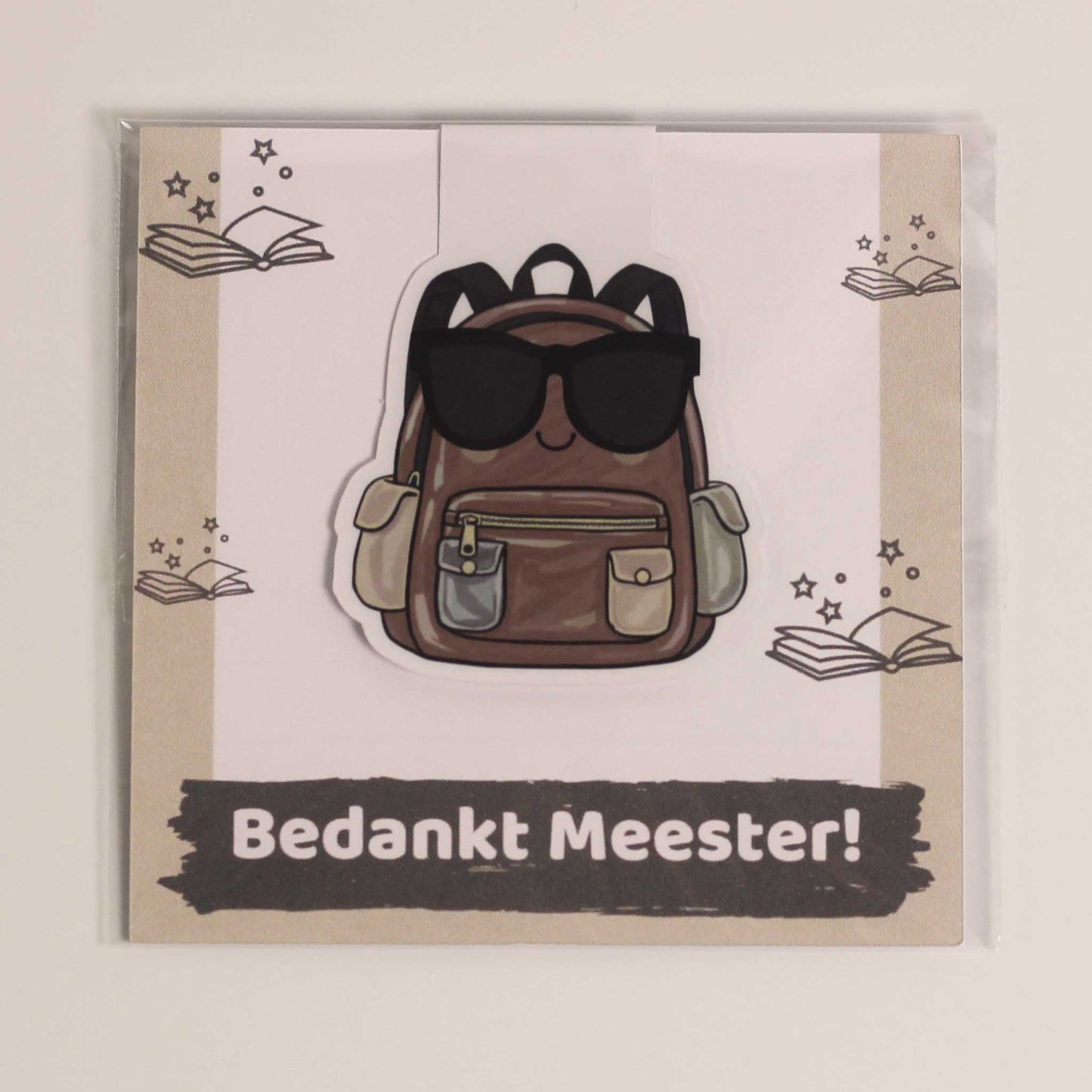 Magnetische boekenlegger voor meester met bruine rugzak en zonnebril op een kaartje met de tekst Bedankt Meester in transparante verpakking