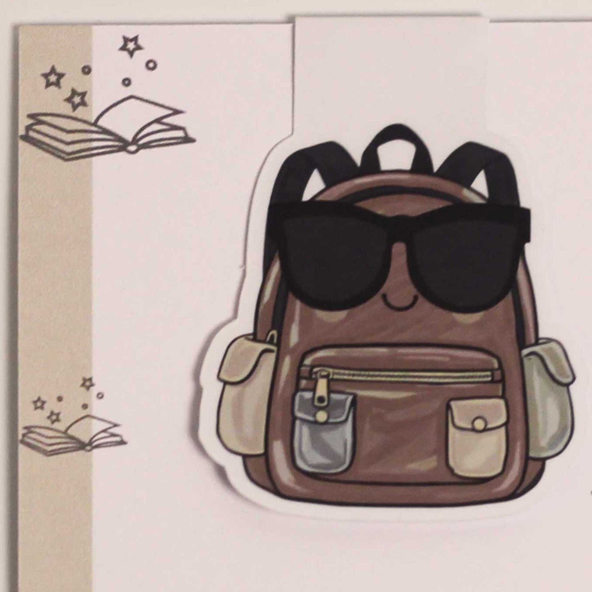 Detailfoto van een magnetische boekenlegger met bruine rugzak, zonnebril en witte rand op een lichte achtergrond