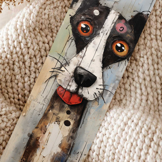 Close-up van boekenlegger met artistieke zwart-witte hond met grote oranje ogen, zwart flapoor en rood tongetje op een beige gebreide deken.