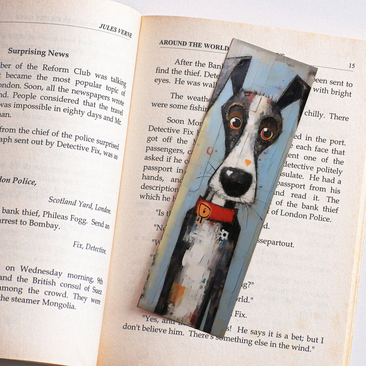 Boekenlegger met artistieke zwart-witte hond en rode halsband tussen de pagina's van een open boek.