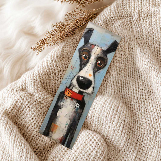 Boekenlegger met zwart-witte hond, grote ogen en rode halsband liggend op een zachte beige gebreide deken.