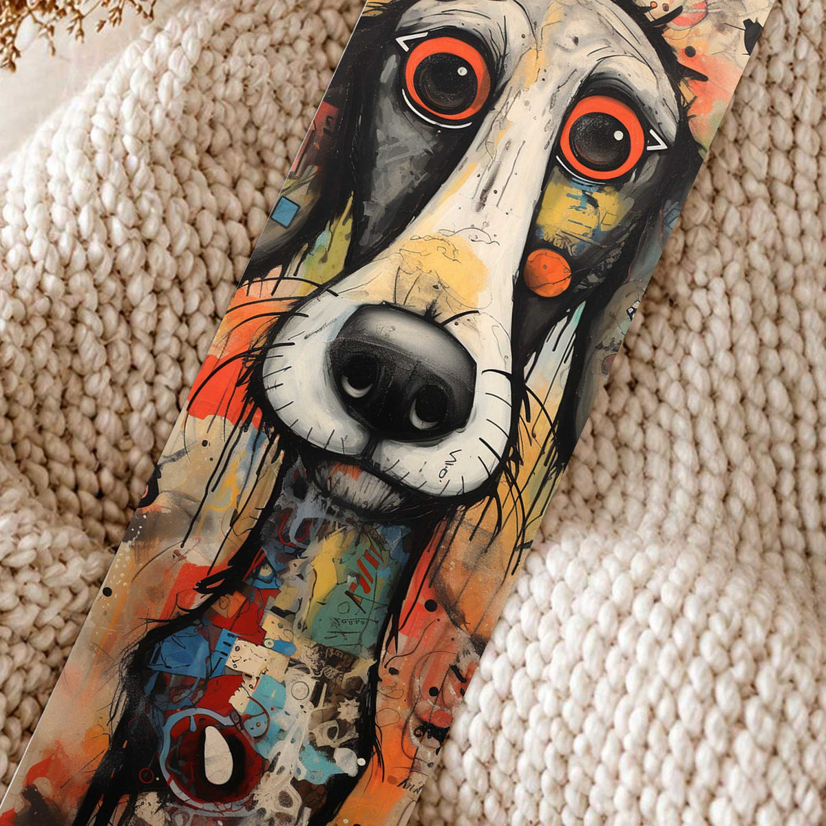 Close-up van boekenlegger Hond Kunst met een langgerekte zwart-witte hond, grote rood-oranje ogen en kleurrijke abstracte details.