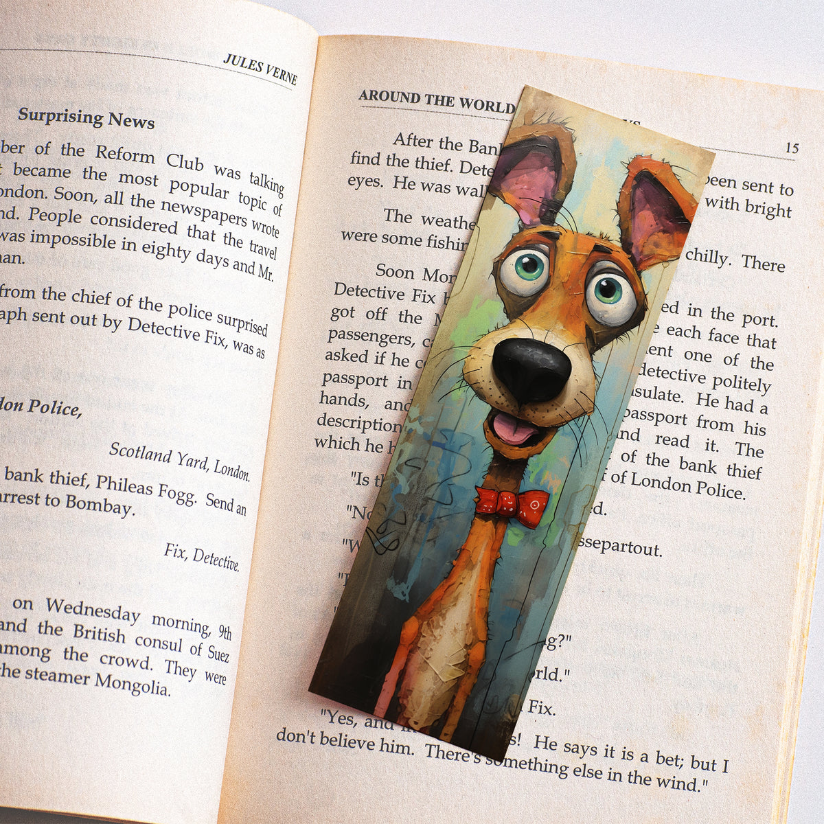 Boekenlegger met kleurrijke oranje hond en rood strikje liggend op de pagina's van een open boek.
