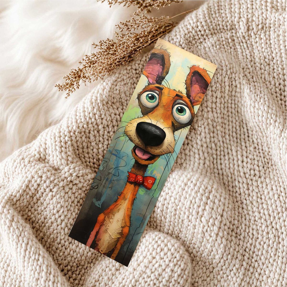 Kleurrijke boekenlegger met oranje hond met grote groene ogen en rood strikje op een zachte beige gebreide deken.